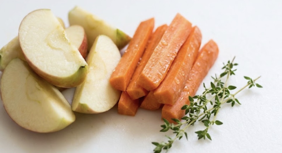 Freshly cut apple slices and carrot sticks with a thyme sprig